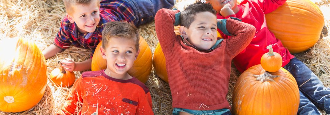 Kids Laying on Top of Hay Bales and Pumpkins