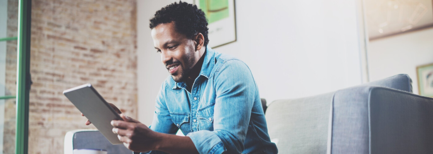 Man Sitting on Couch Using Tablet