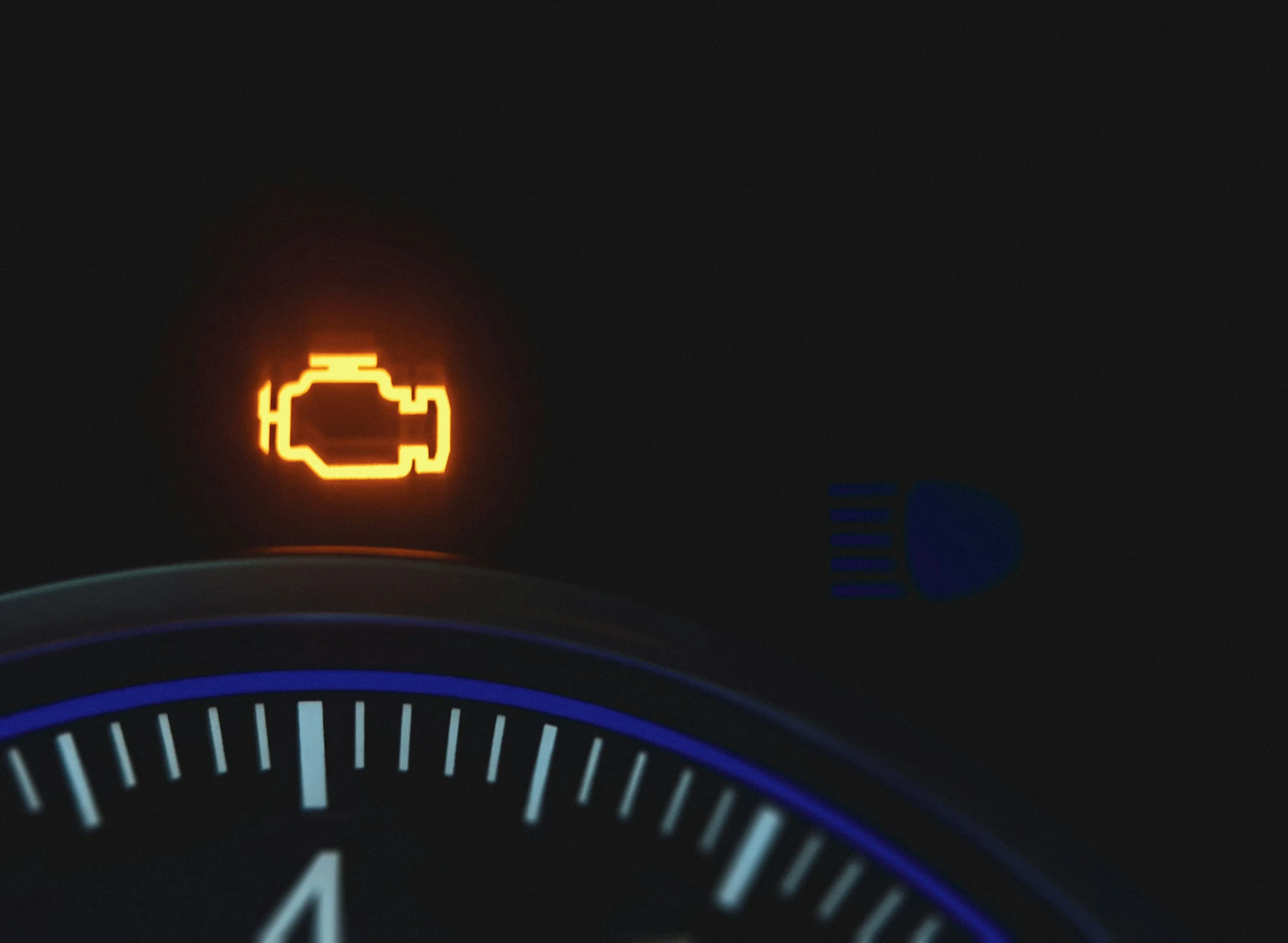 Close-up of an illuminated check engine warning light on a vehicle dashboard