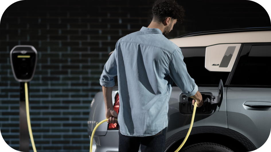 A man charges his MINI Countryman SE ALL4 against a brick wall. 