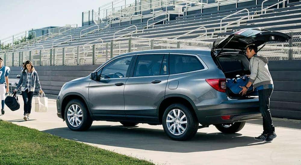 Family loading gear into a silver 2020 Honda Pilot LX after a football game