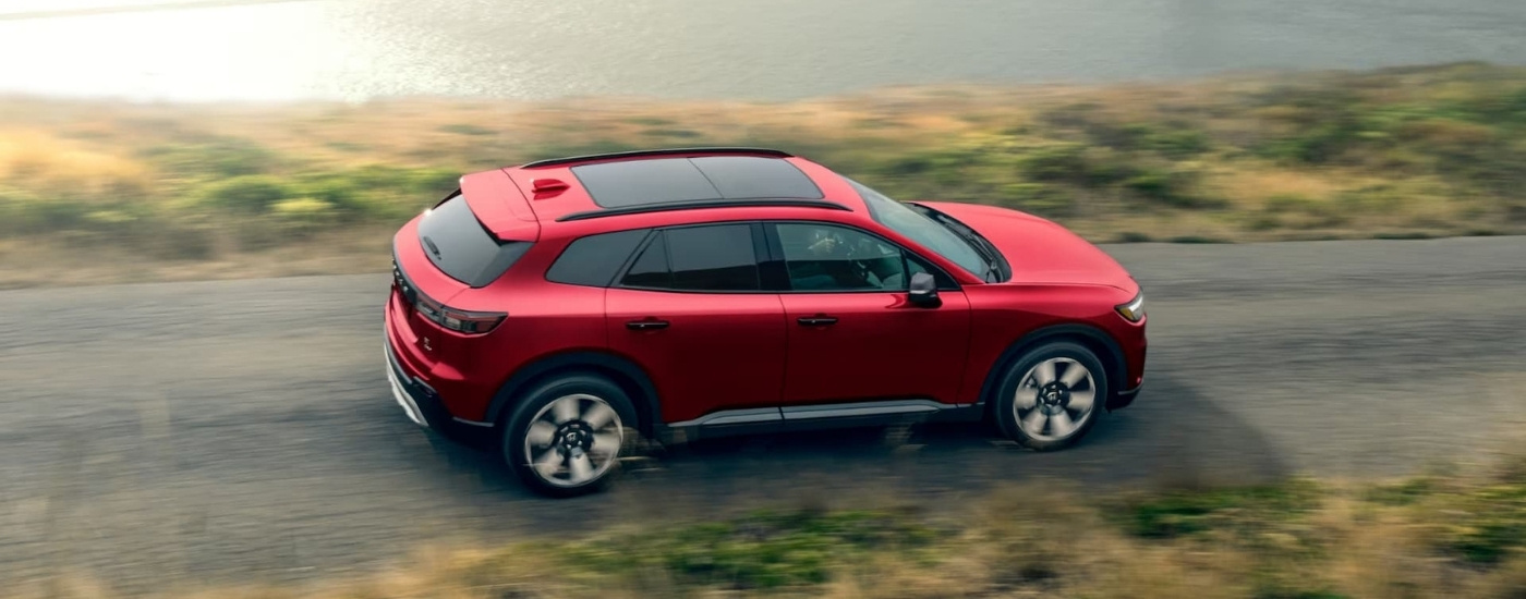 Red 2025 Honda Prologue Elite is shown driving on a backroad