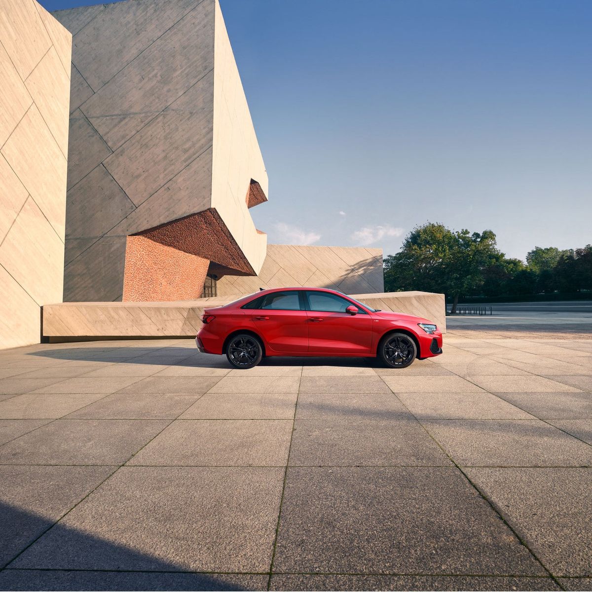 Red 2026 Audi A3 Premium sedan parked outside a modern concrete building