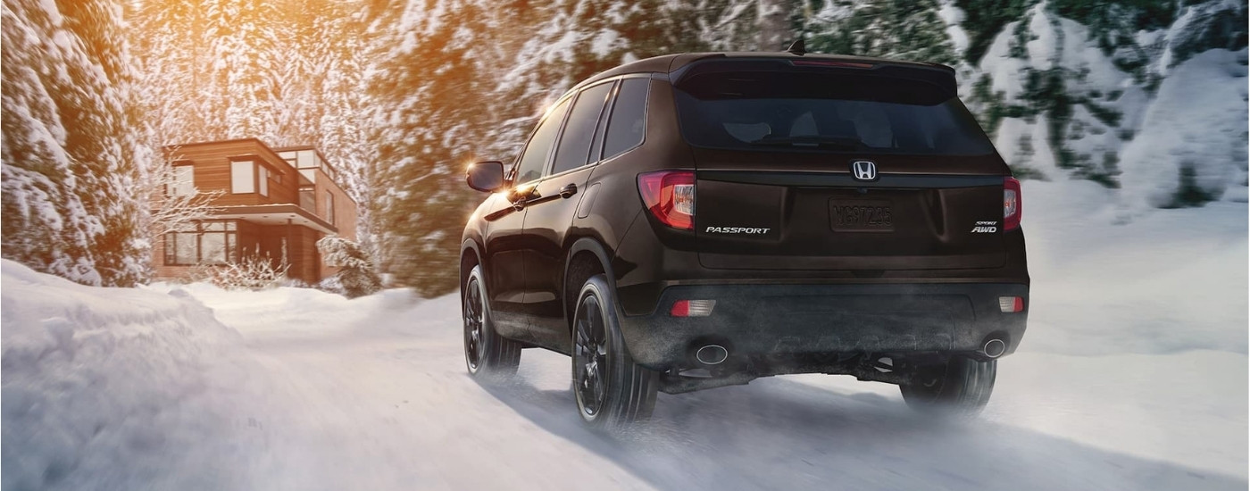 Black 2021 Honda Passport Sport driving toward a cabin