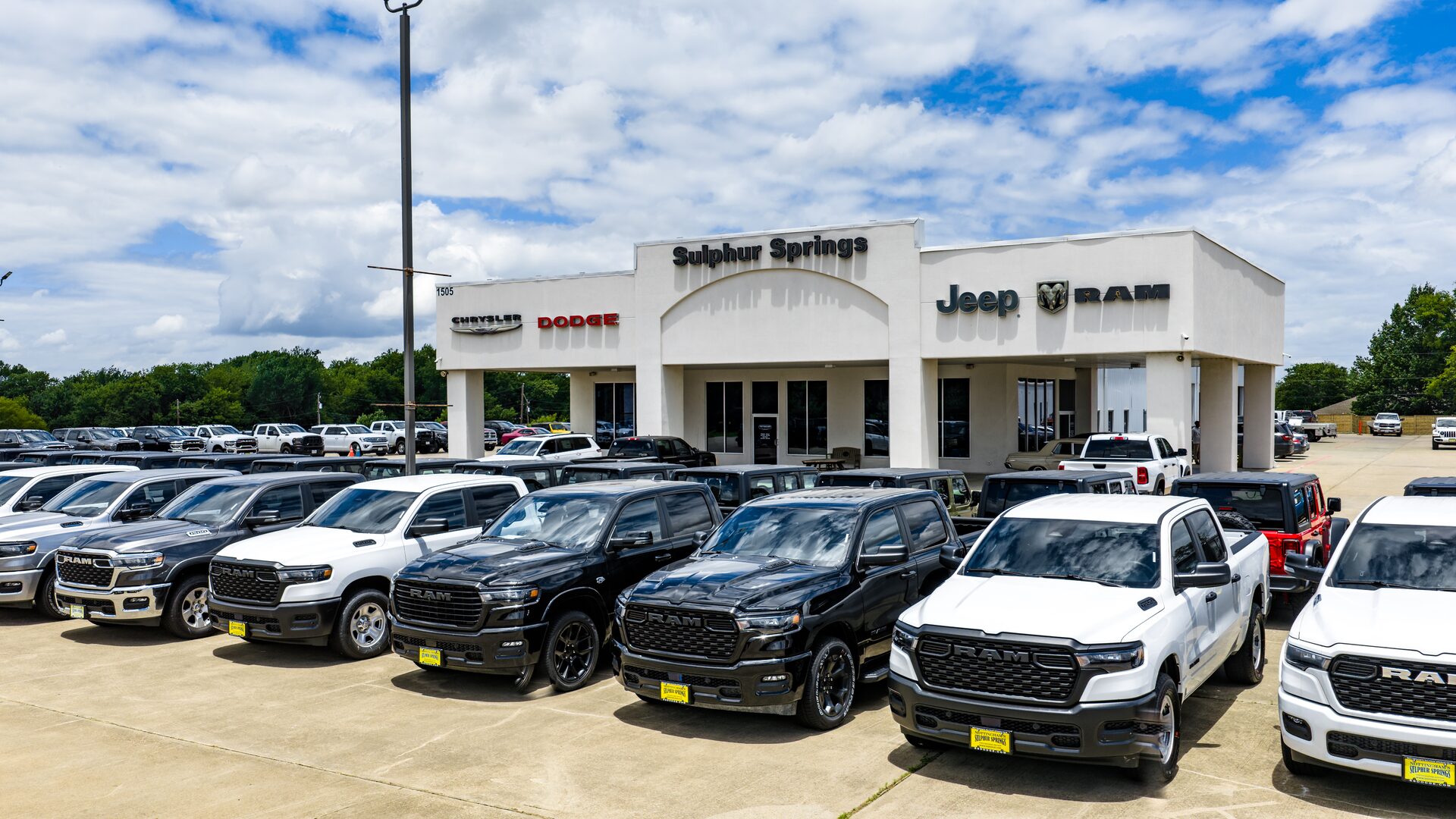 Exterior of Sulphur Springs Chrysler Dodge Jeep Ram with trucks parked in front.