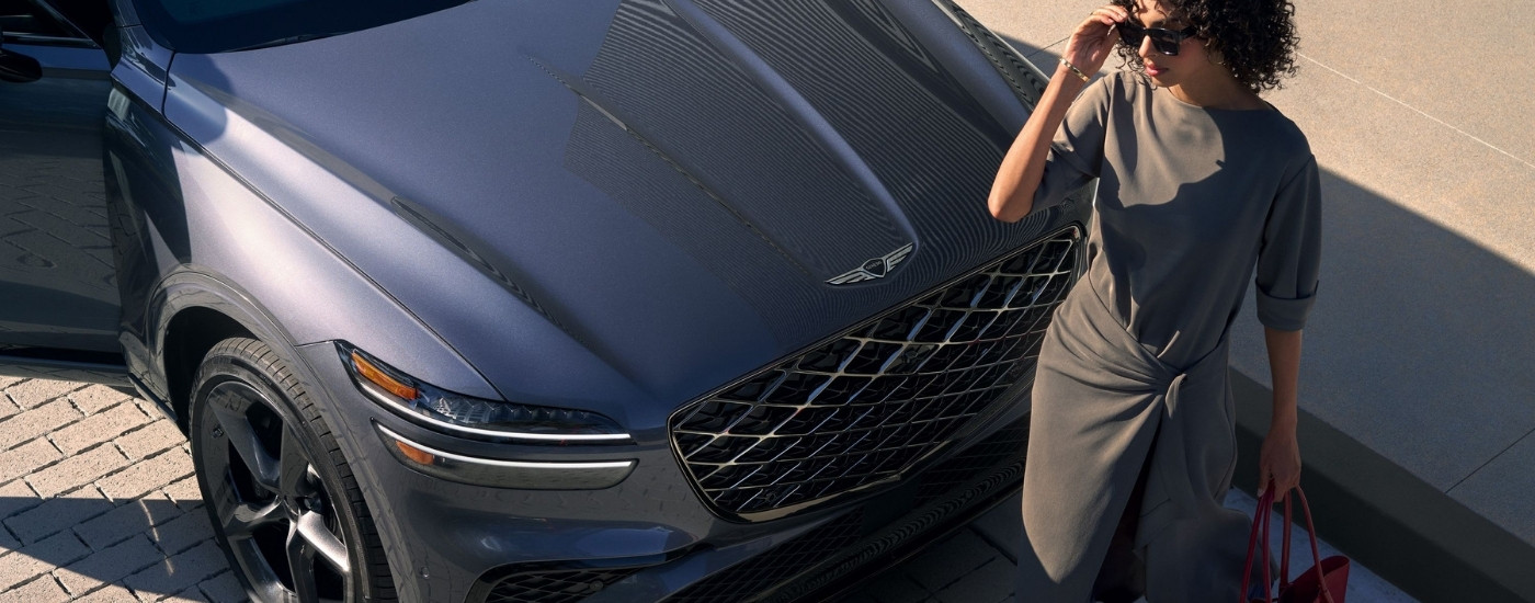 Person standing in front of a grey 2027 Genesis GV70