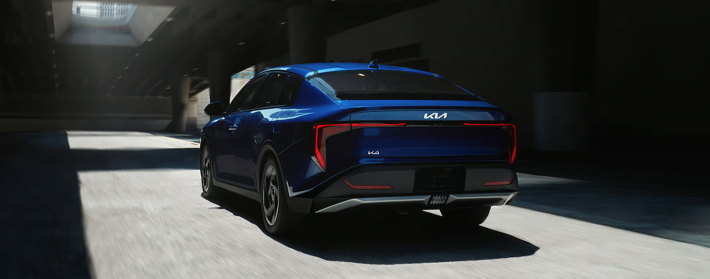 Rear of a blue 2026 Kia K4 driving through a tunnel.