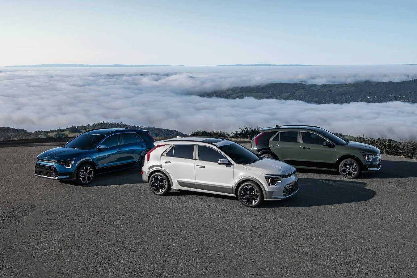 Three 2026 Kia Niro in blue, white, and green parked at a mountain overlook, representing the current Kia Niro financing offer