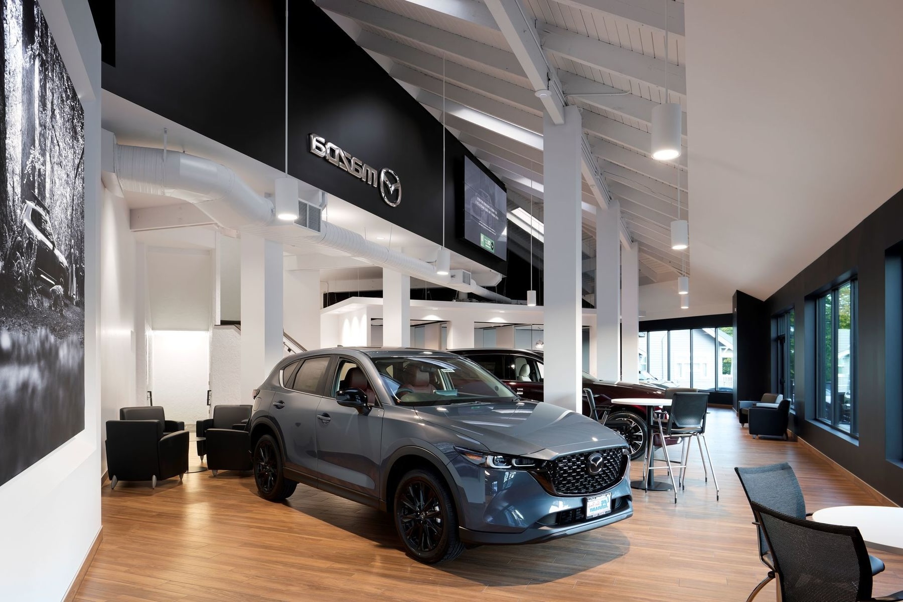 Technician performing maintenance on a Mazda vehicle in a service bay