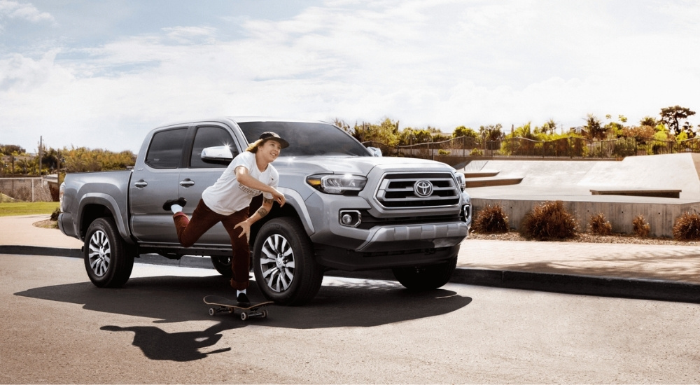 Person skateboarding next to a silver 2022 Toyota Tacoma