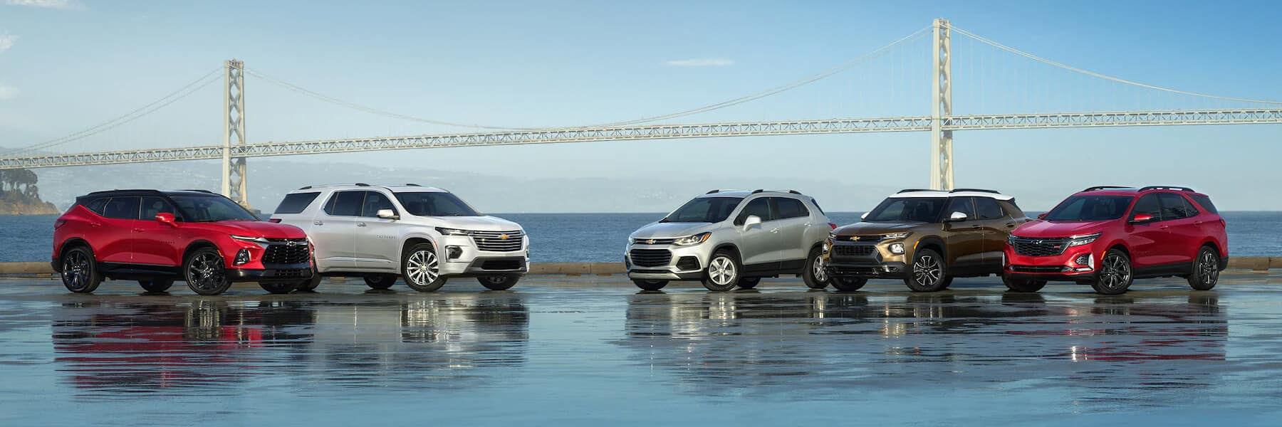 multiple Chevrolet SUVs parked in front of a bridge