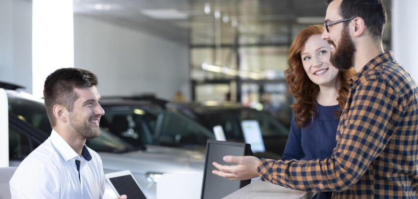 Excited Couple Reviewing Trade in Offer with Salesman