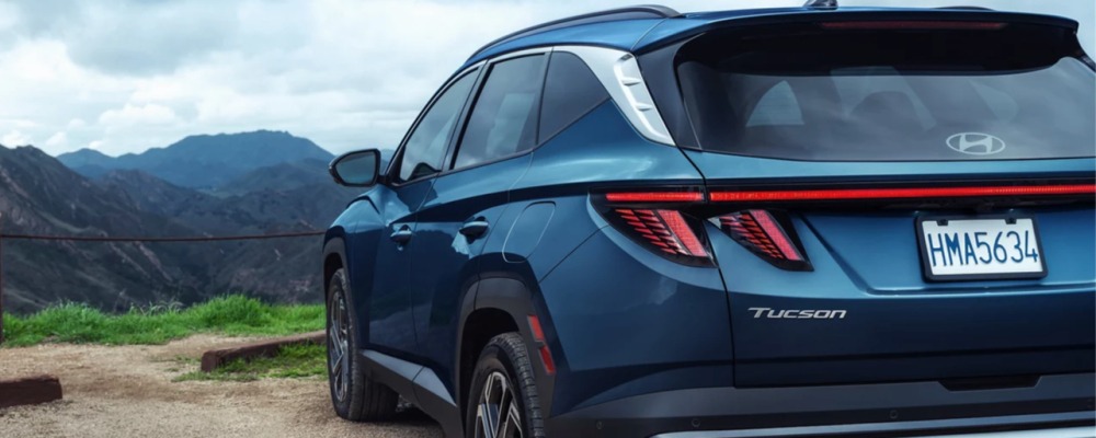 Rear view of a blue Hyundai Tucson Hybrid at a mountain overlook