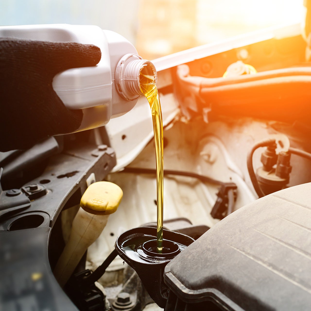 Fresh motor oil being poured into a car engine