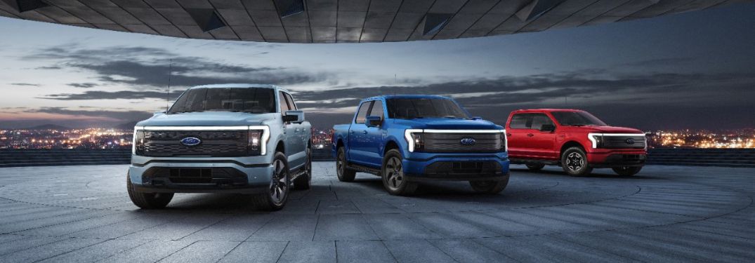 White, Blue and Red 2023 Ford F-150 Lightning Models in a Driveway