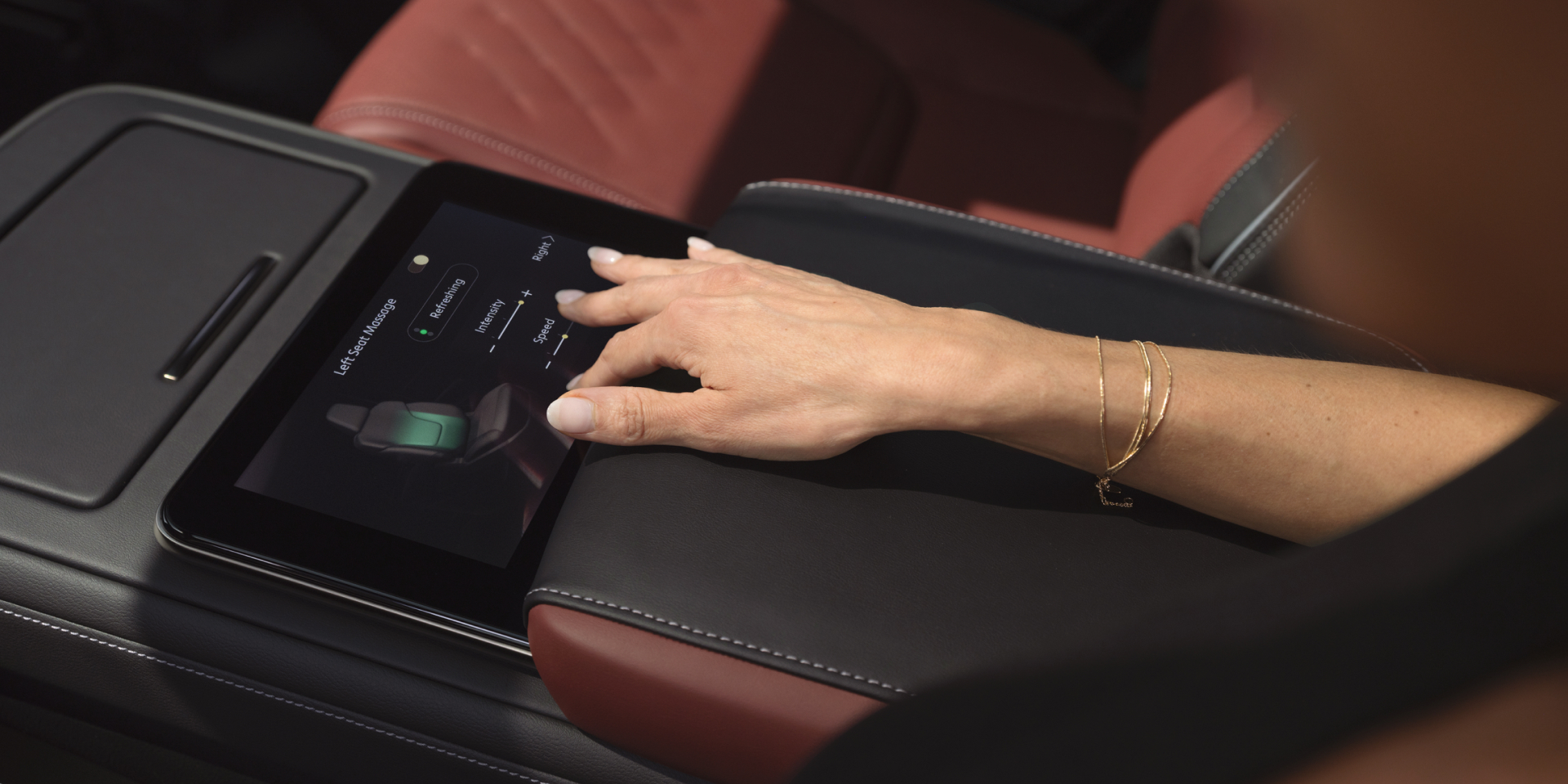 Close-up of a hand using the 2027 INFINITI QX80 touchscreen to adjust left-seat massage intensity and speed settings.