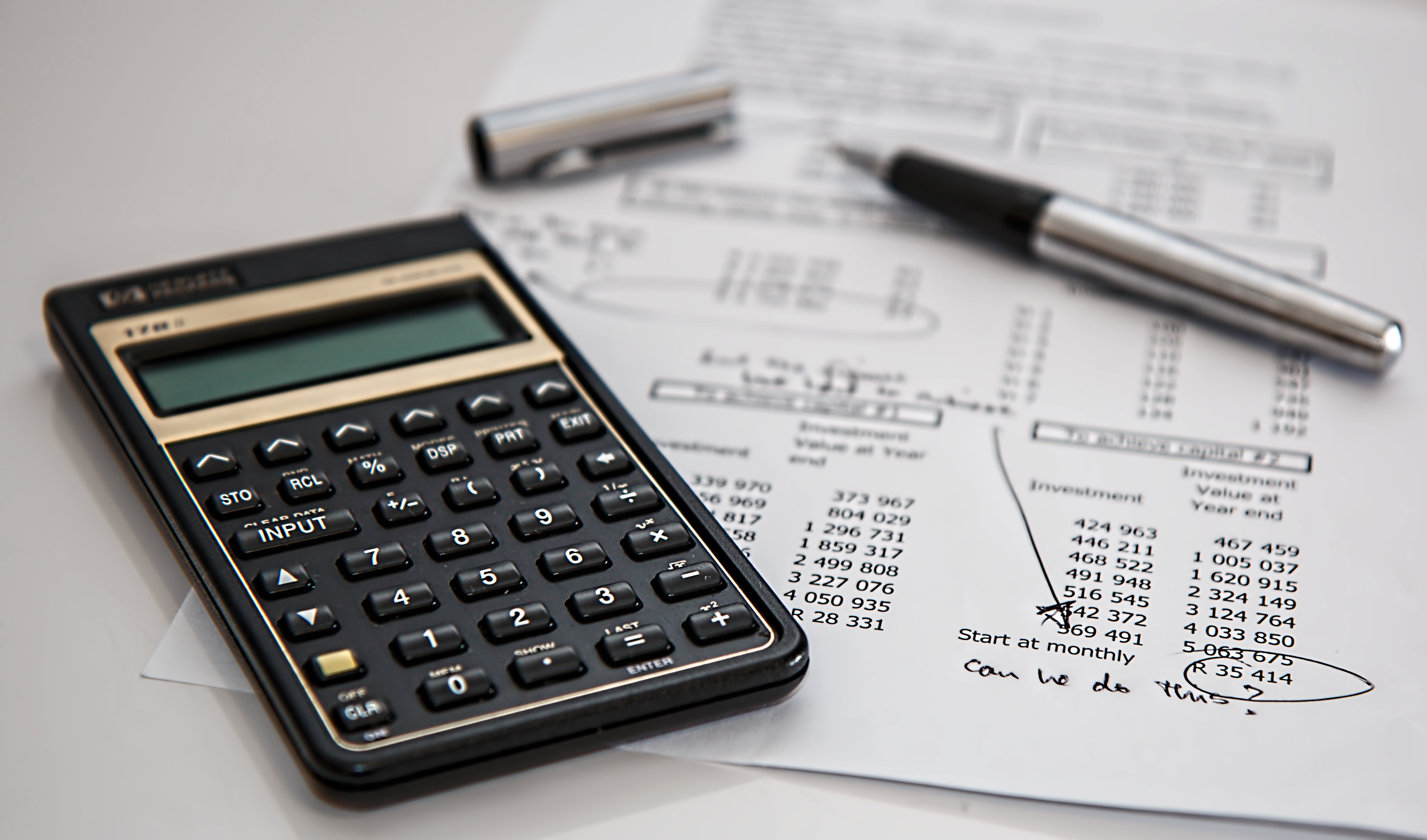 Calculator, pen and financial paperwork on a desk
