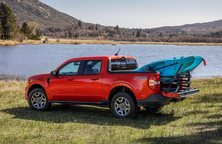 Red 2024 Ford Maverick with a Blue Kayak in the Bed Next to a Lake