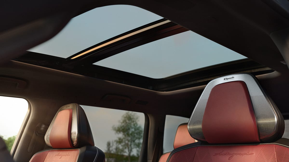 Interior of the 2027 INFINITI QX80 Autograph with burgundy diamond-quilted leather seats, Klipsch headrest speakers, and an open dual-pane panoramic sunroof.