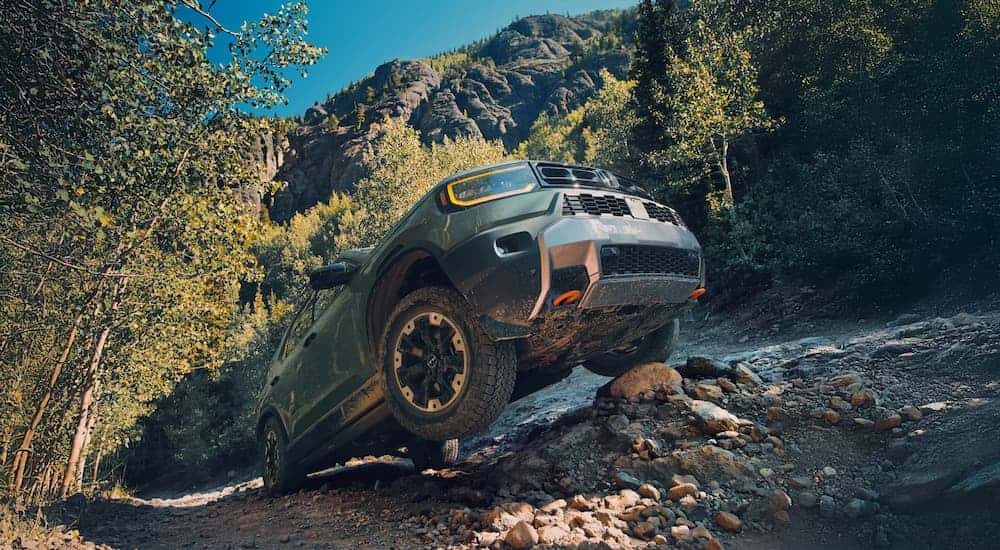Low angle view of a green 2026 Honda Passport TrailSport Elite driving up a steep cliff.
