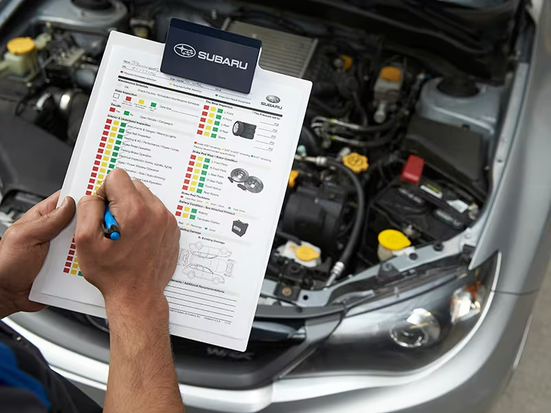 A mechanic performing an inspection on a Subaru vehicle.