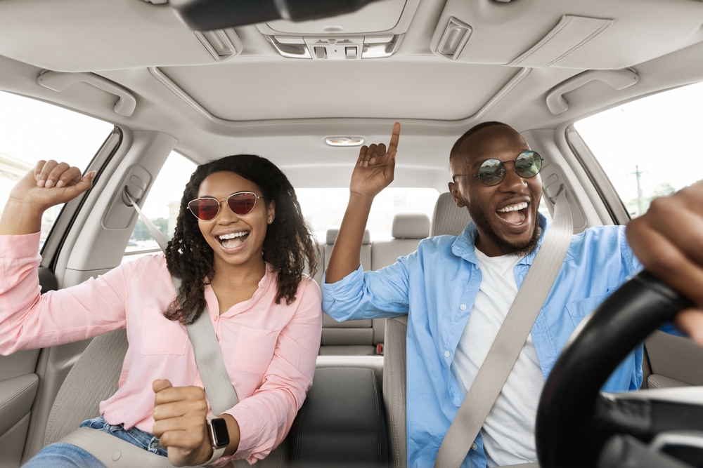 happy couple moving and grooving to music inside of their vehicle