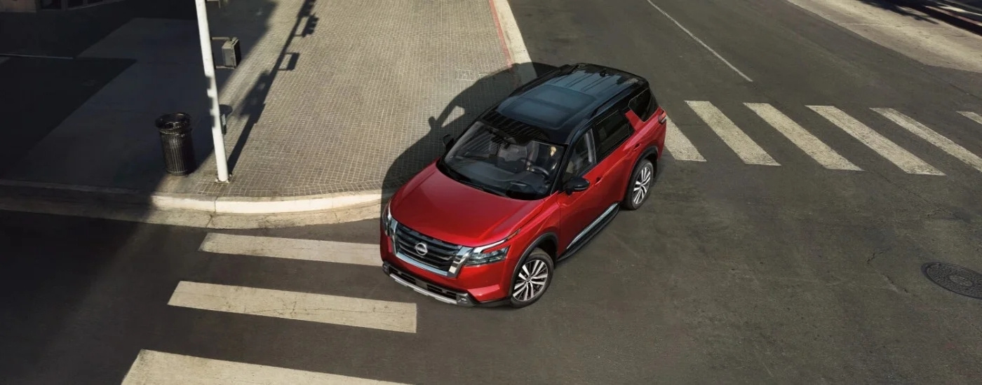 Nissan Pathfinder Platinum 2025 rojo conduciendo a través de una intersección