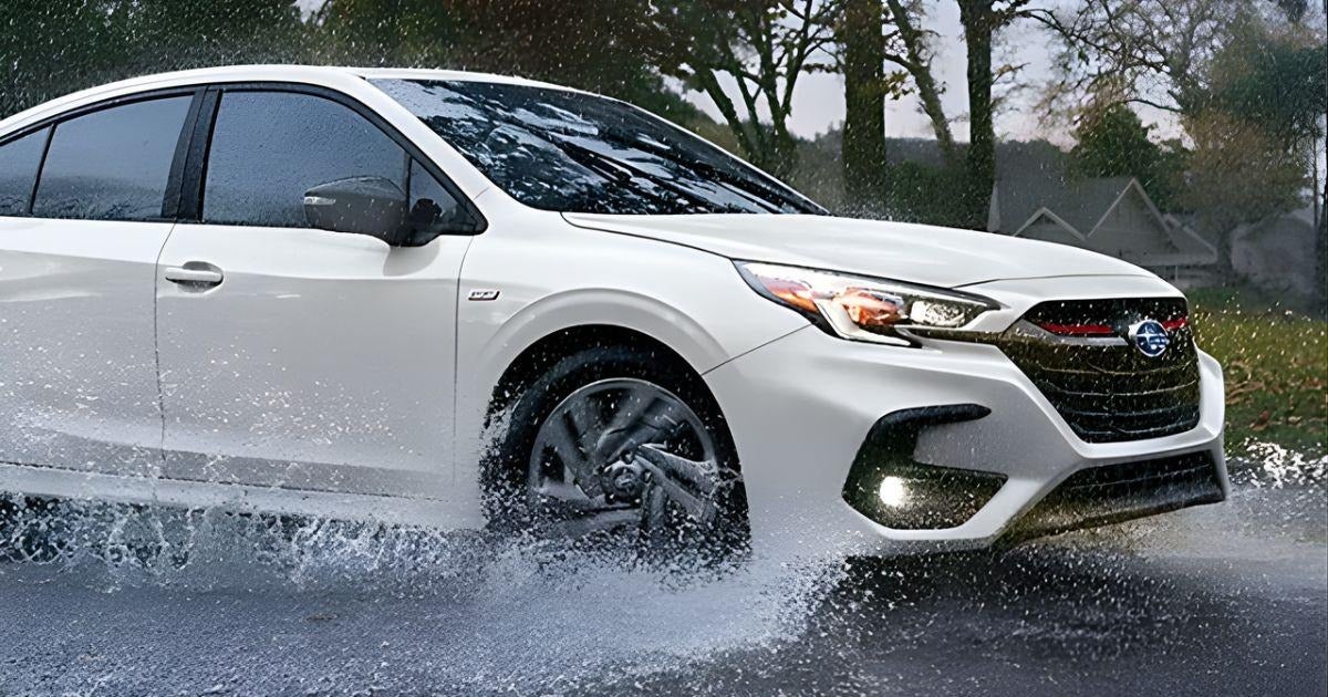 White 2025 Subaru Legacy Sport splashing through water on a wet road