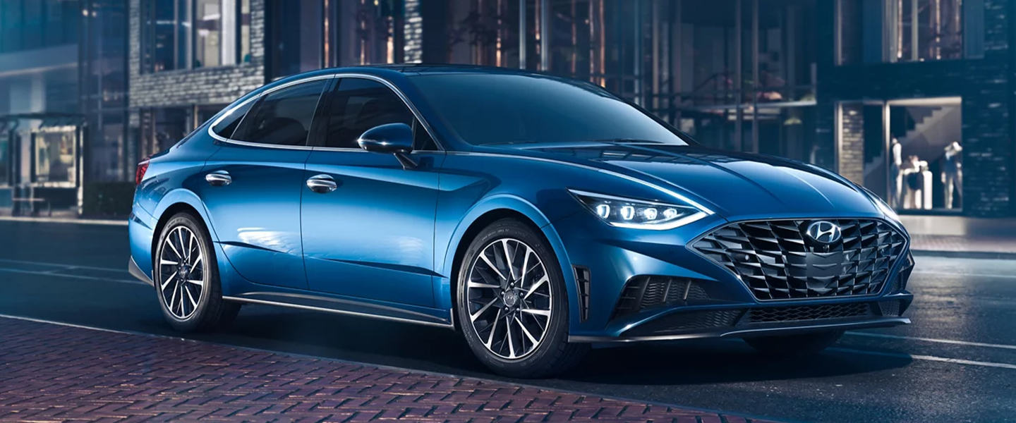 a blue sedan parked next to a brick sidewalk