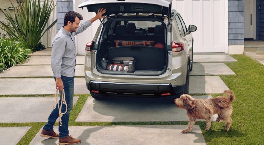 Man opening back of a grey 2024 Nissan Rogue.