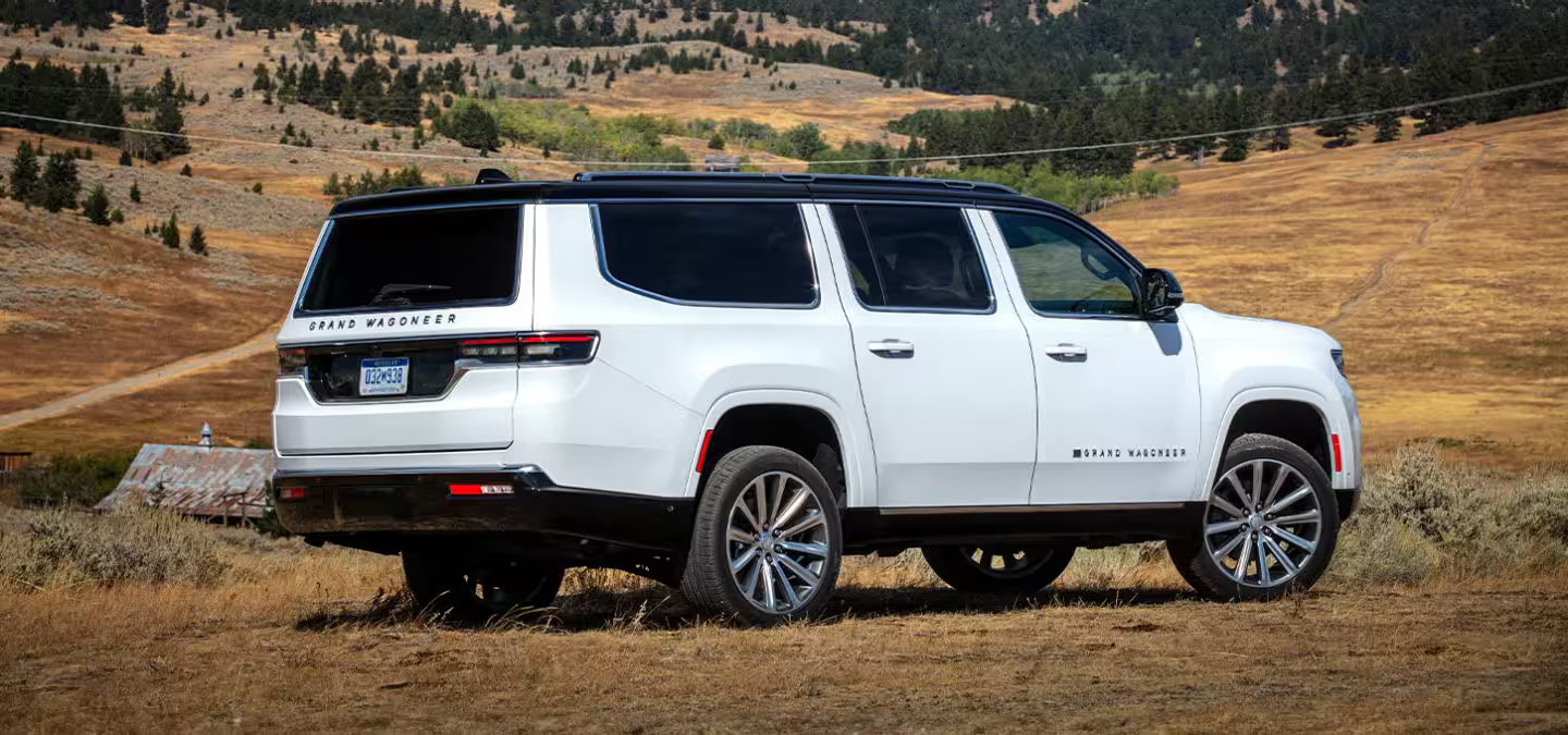 A white suv sitting parked on a hill.