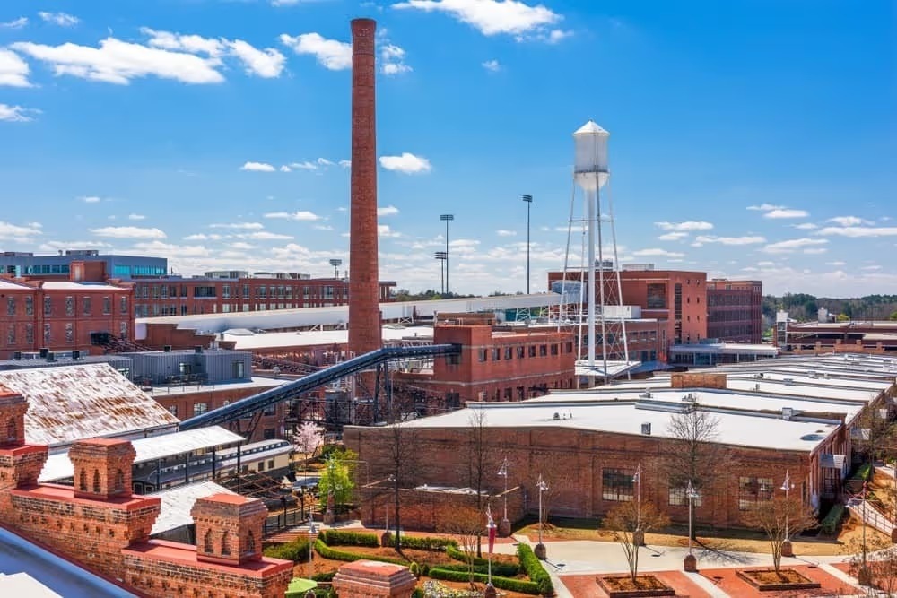 Historic brick tobacco warehouses with a smokestack and water tower in Durham