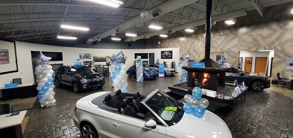 Volkswagen and Audi showroom in Springfield decorated with balloons, with a VW Atlas and VW Beetle on display