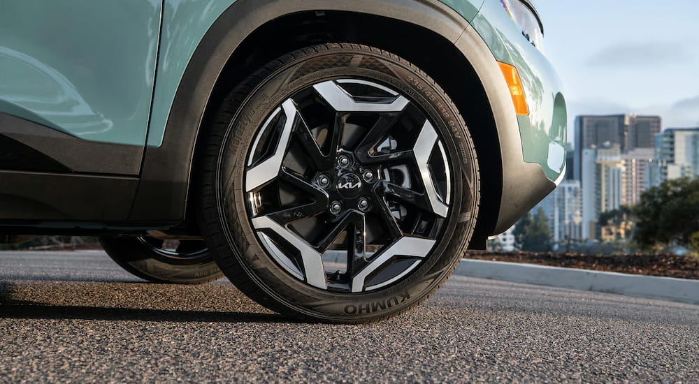 Close-up on the wheel of a blue 2026 Kia Seltos parked on a road.