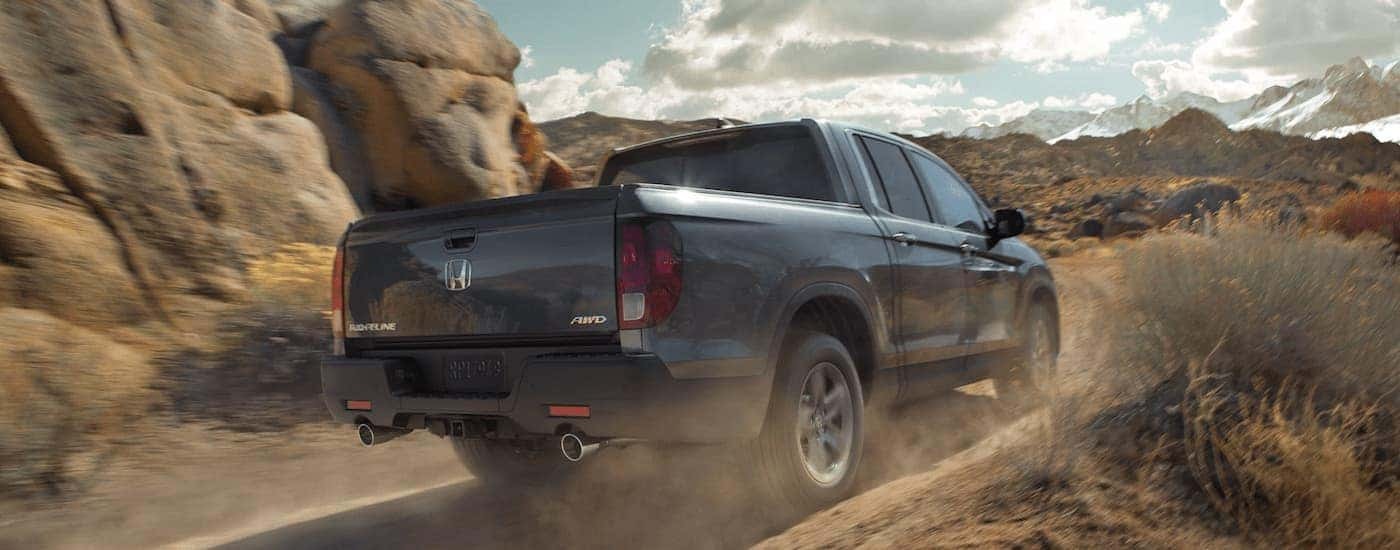 A grey 2024 Honda Ridgeline is shown from the rear at an angle.