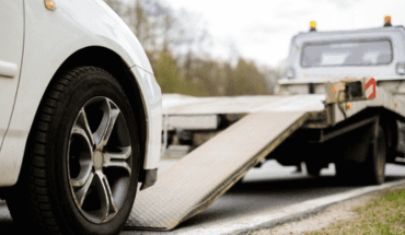 White car next to a flatbed tow truck