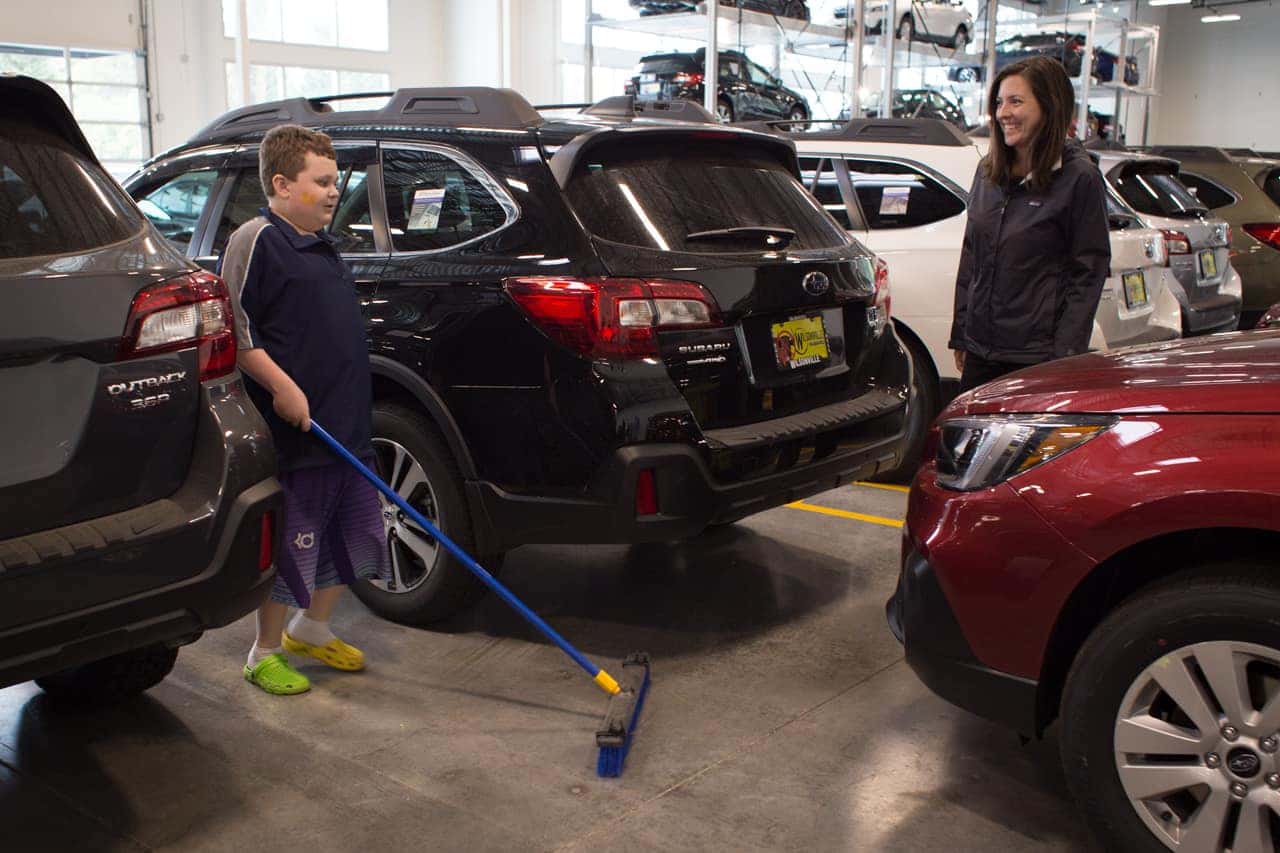 Victory Academy intern sweeping between cars in the showroom