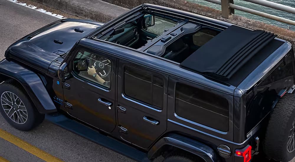 The top of a black 2024 Jeep Wrangler driving on a bridge.