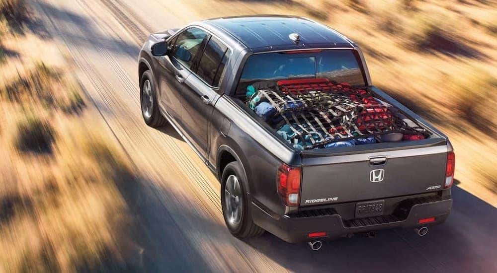 A grey 2021 Honda Ridgeline RTL-E is shown from a high angle driving on a dirt path.