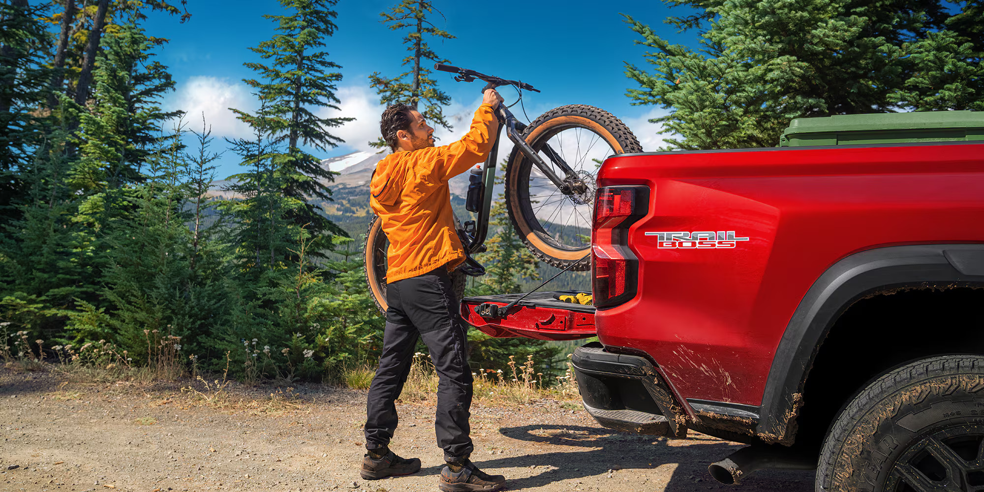 A man putting a bike into the back of a red truck.