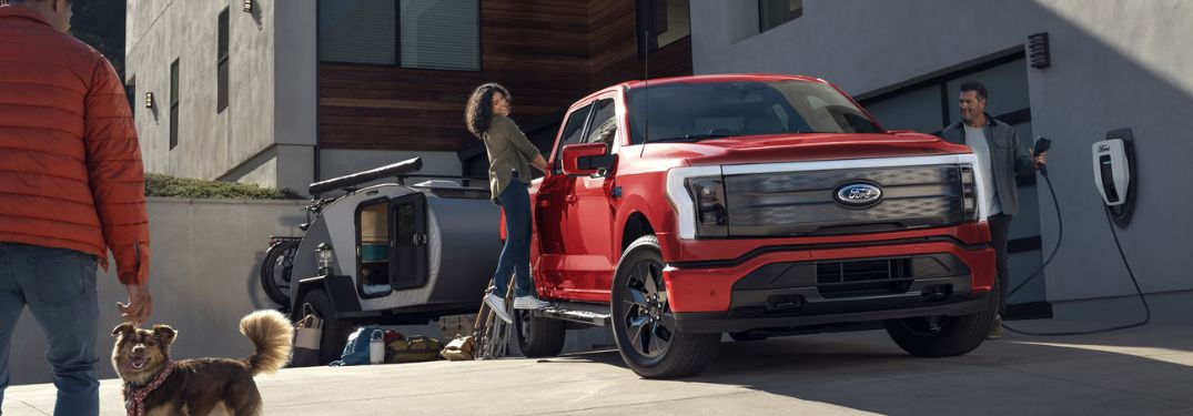 Red 2025 Ford F-150 Lightning Being Charged in Driveway