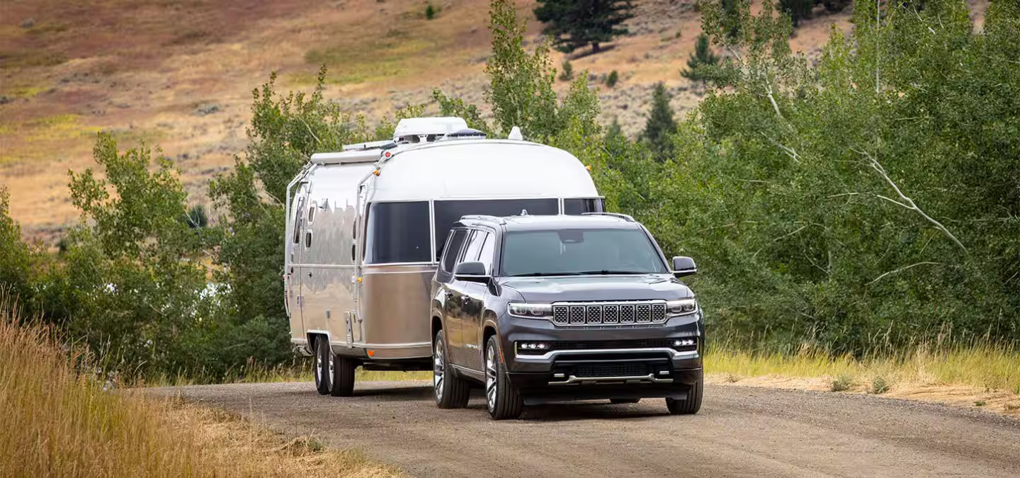 A black suv pulling a mobile home.