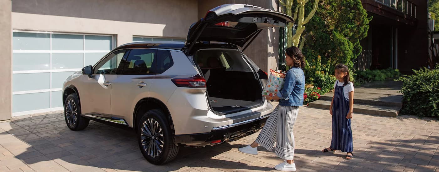 Family putting shopping bags in the back of a grey 2026 Nissan Rogue