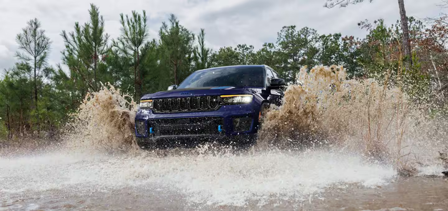 A blue jeep driving through water.