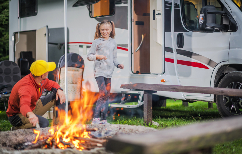 father and daughter by a fire at their RV campsite