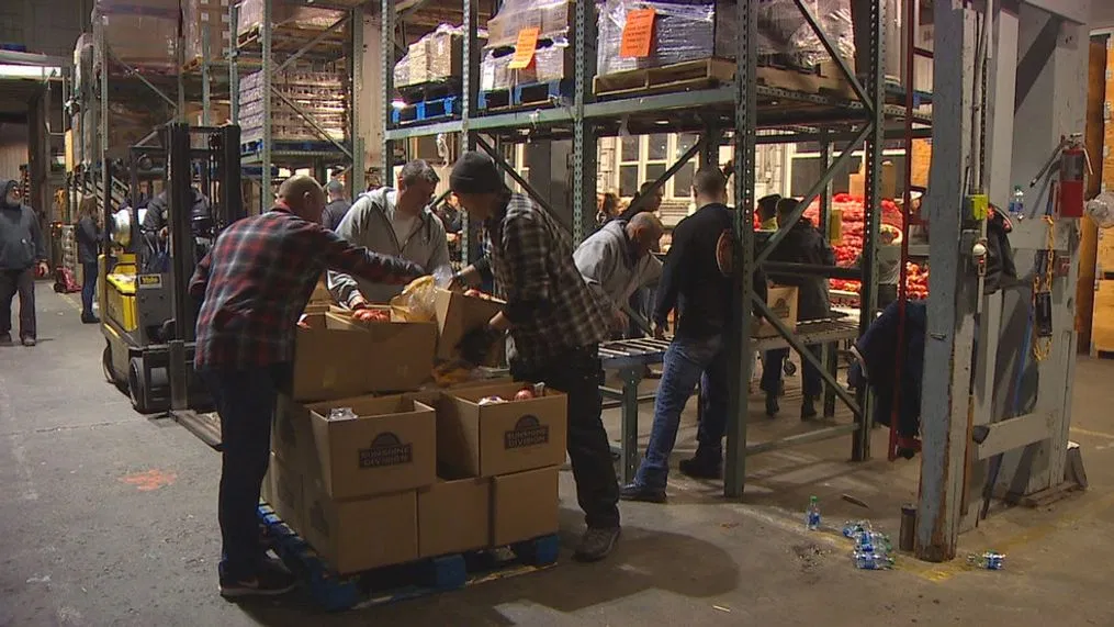 Volunteers stacking holiday food boxes in a warehouse