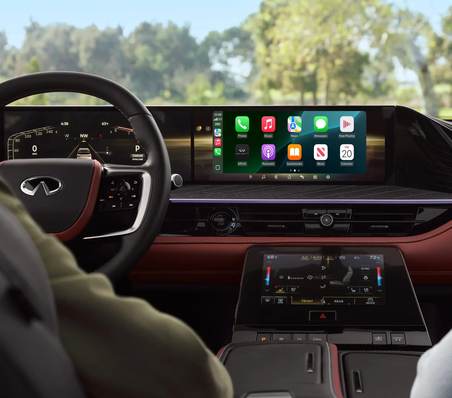 Driver’s cockpit of the 2027 INFINITI QX80 with Apple CarPlay on the wide center screen, a digital cluster, burgundy leather accents, and a tree-lined road through the windshield.
