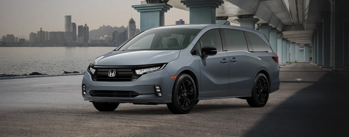 Silver 2023 Honda Odyssey parked under a bridge in front of a city skyline