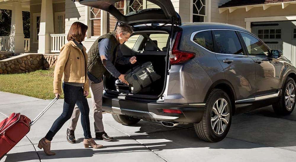 A couple is loading luggage into the back of their grey 2020 Honda CR-V Touring outside of their Rochester, NY home.