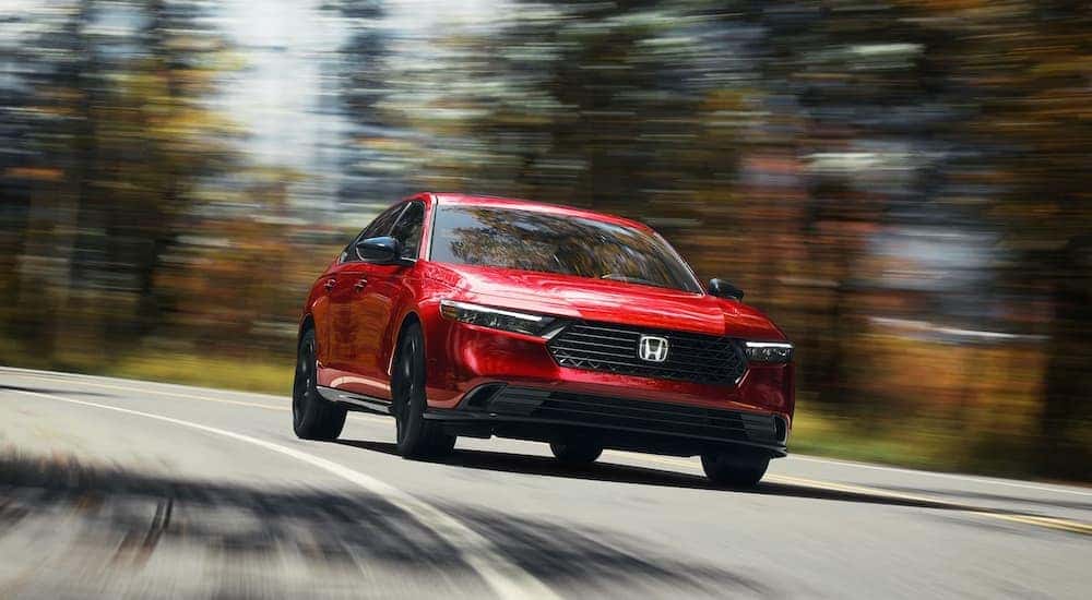 Red 2023 Honda Accord Sport-L driving on a forest road